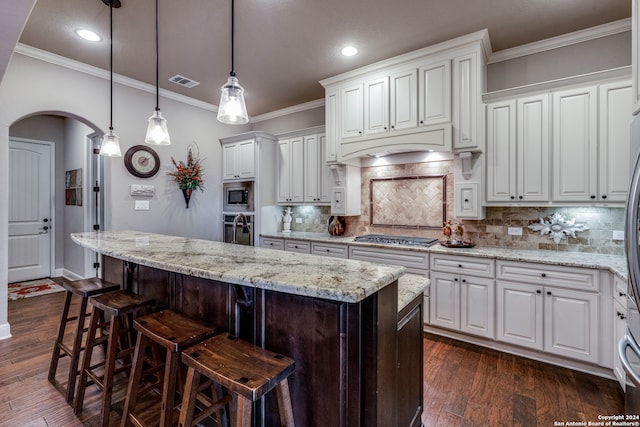 kitchen with appliances with stainless steel finishes, white cabinetry, a kitchen island with sink, and dark hardwood / wood-style flooring