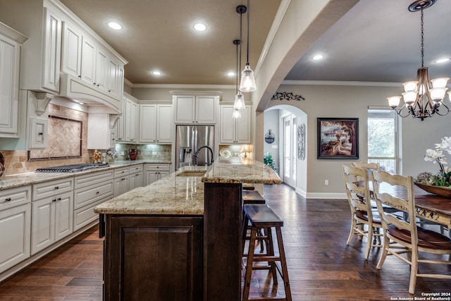 kitchen with white cabinets, a kitchen island with sink, sink, dark wood-type flooring, and decorative light fixtures