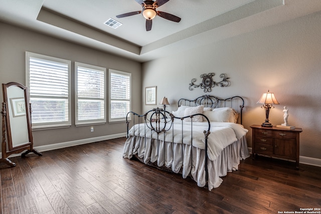 bedroom featuring dark hardwood / wood-style floors, a raised ceiling, and ceiling fan