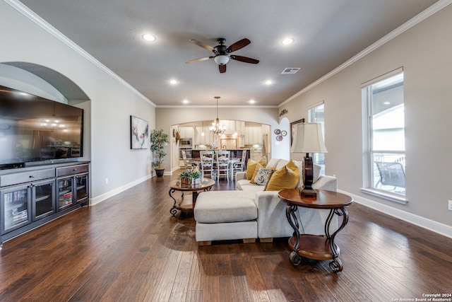 living room featuring dark wood-type flooring, ornamental molding, and ceiling fan with notable chandelier