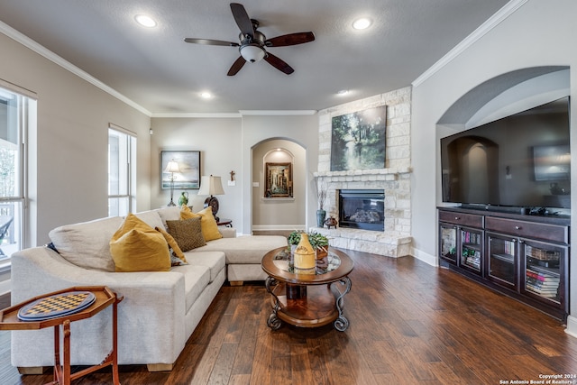 living room with dark wood-type flooring, crown molding, a textured ceiling, a fireplace, and ceiling fan