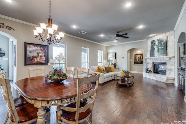 dining area with ceiling fan with notable chandelier, crown molding, dark hardwood / wood-style flooring, and a fireplace