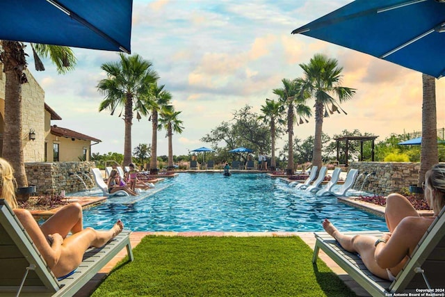 view of pool with pool water feature and a yard