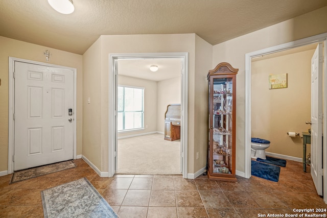 carpeted entrance foyer featuring a textured ceiling