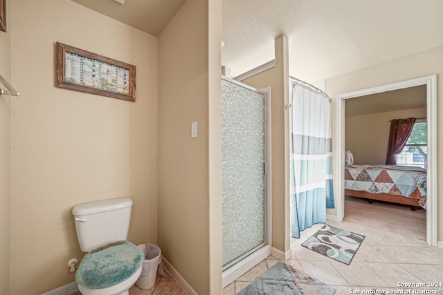 bathroom with a textured ceiling, tile patterned flooring, toilet, and walk in shower