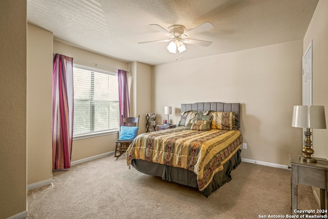 bedroom featuring ceiling fan, a textured ceiling, and light colored carpet