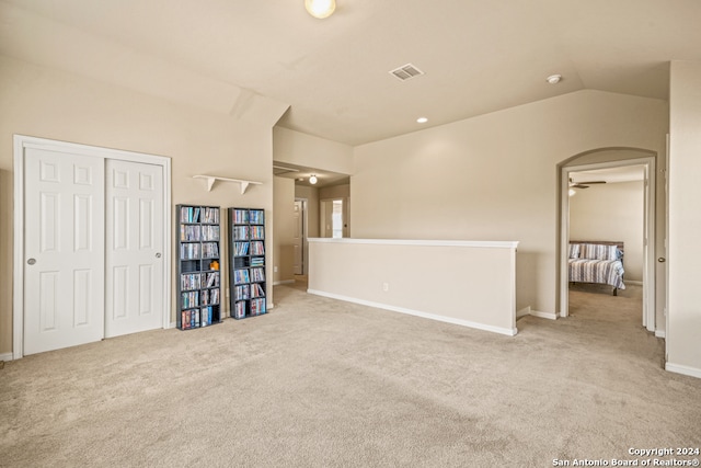 empty room with lofted ceiling, light colored carpet, and ceiling fan