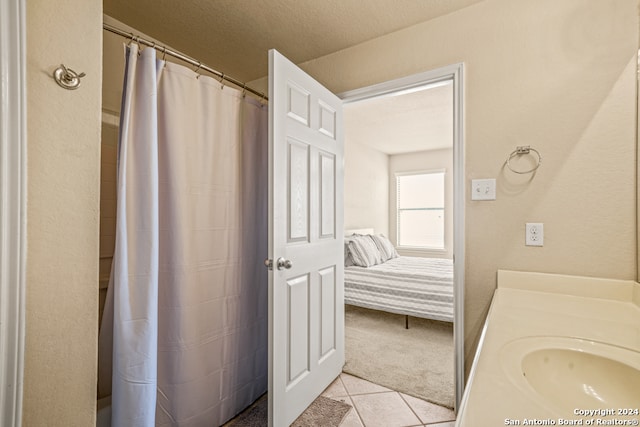 bathroom with a textured ceiling, sink, tile patterned floors, and a shower with shower curtain