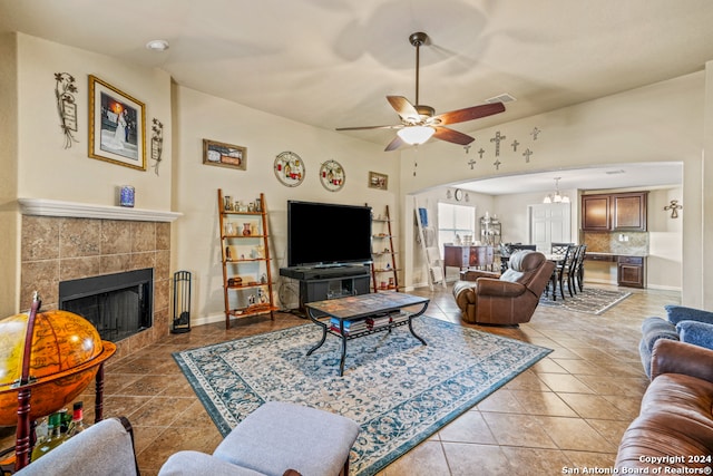 tiled living room featuring ceiling fan with notable chandelier and a tile fireplace