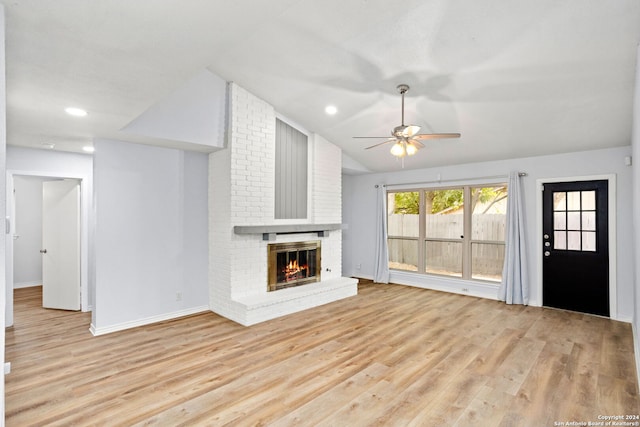 unfurnished living room with light hardwood / wood-style floors, a brick fireplace, vaulted ceiling, and ceiling fan