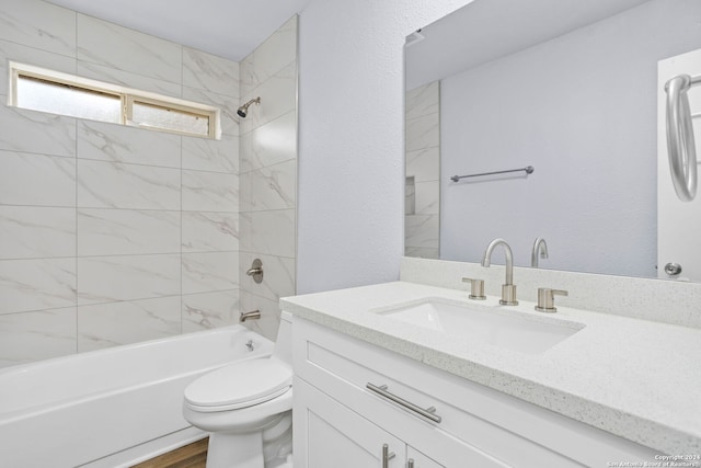 full bathroom with tiled shower / bath, vanity, wood-type flooring, and toilet