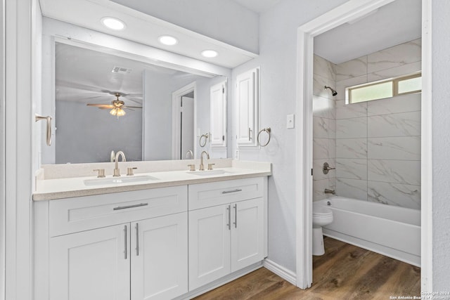 full bathroom featuring toilet, tiled shower / bath, hardwood / wood-style floors, vanity, and ceiling fan