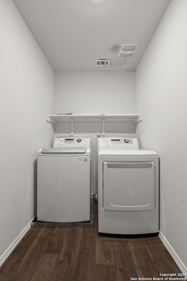 clothes washing area with dark hardwood / wood-style flooring and washer and clothes dryer