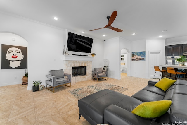 living room featuring light tile patterned flooring, ceiling fan, ornamental molding, and a fireplace