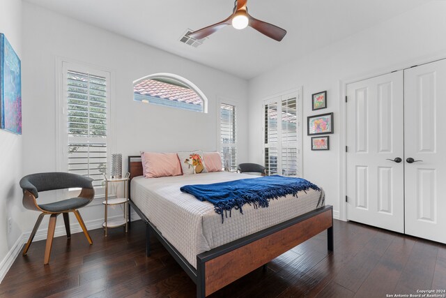 bedroom with a closet, multiple windows, ceiling fan, and dark hardwood / wood-style floors