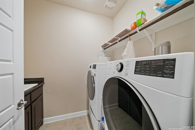 clothes washing area featuring cabinets, washer and clothes dryer, and light tile patterned floors