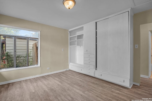 unfurnished bedroom featuring a closet, multiple windows, and light wood-type flooring