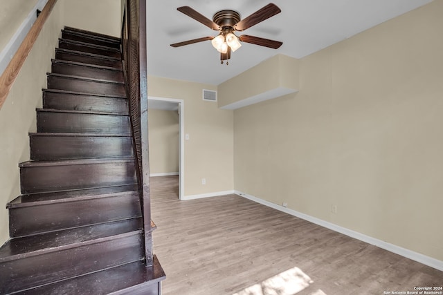 stairway with wood-type flooring and ceiling fan