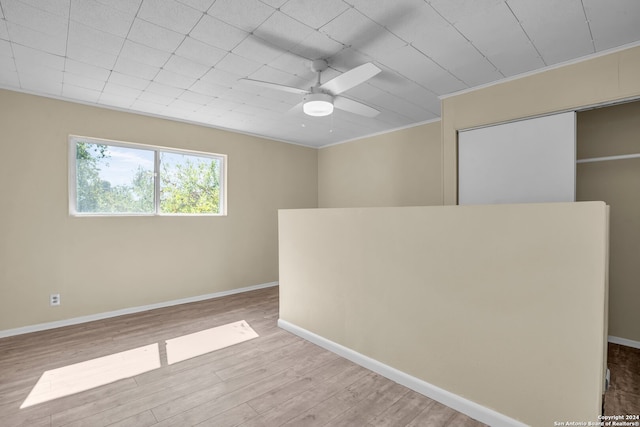 empty room with crown molding, light wood-type flooring, and ceiling fan