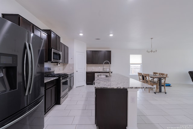 kitchen featuring appliances with stainless steel finishes, sink, an island with sink, decorative light fixtures, and decorative backsplash