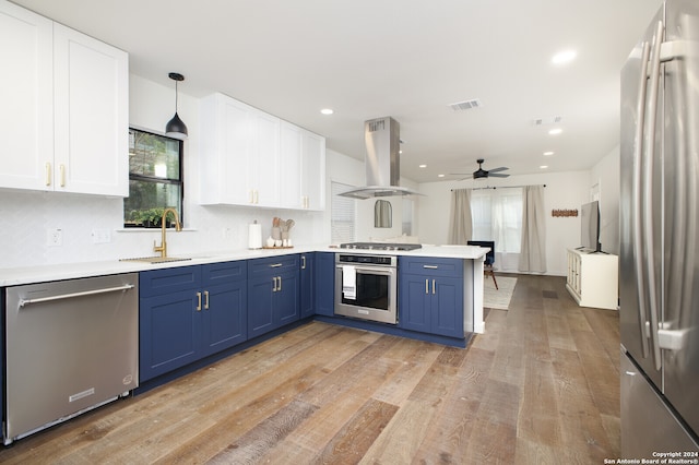 kitchen with a healthy amount of sunlight, stainless steel appliances, decorative light fixtures, and island range hood