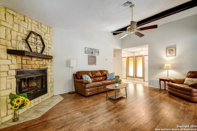 living room featuring a fireplace, hardwood / wood-style flooring, a textured ceiling, high vaulted ceiling, and ceiling fan