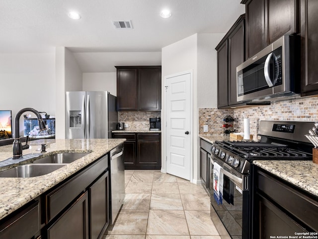 kitchen with sink, stainless steel appliances, dark brown cabinetry, light stone counters, and decorative backsplash