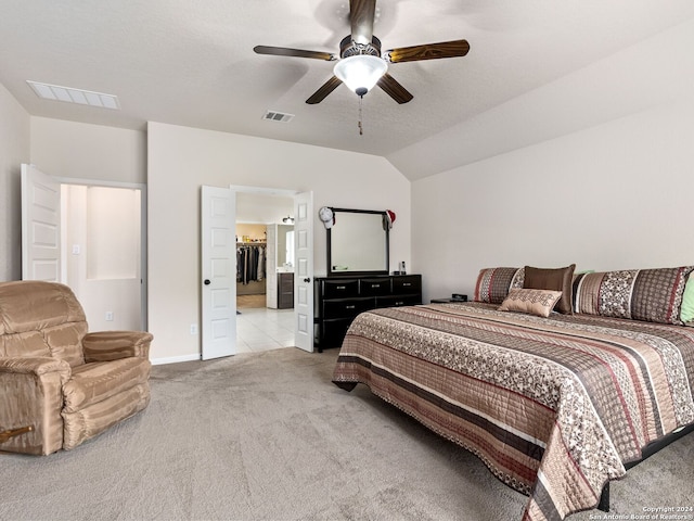 bedroom with a textured ceiling, ceiling fan, lofted ceiling, connected bathroom, and light colored carpet