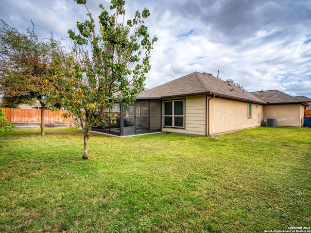 back of property with central air condition unit, a yard, and a sunroom