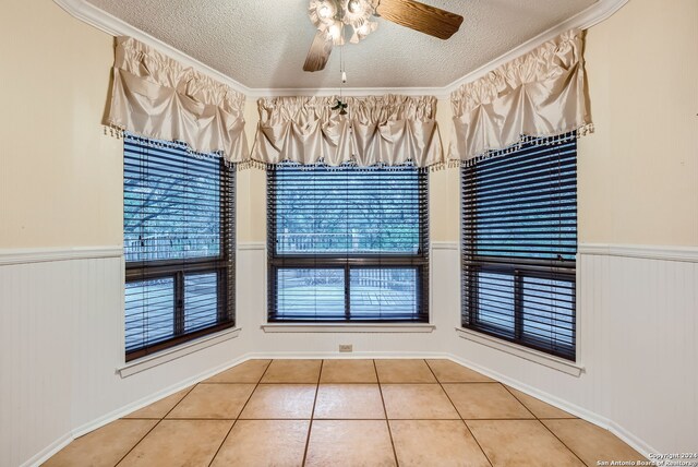 interior space with crown molding, a textured ceiling, wooden walls, and ceiling fan