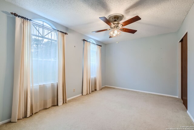 carpeted empty room with a textured ceiling and ceiling fan