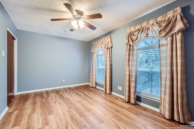 spare room with ceiling fan, a textured ceiling, and light wood-type flooring