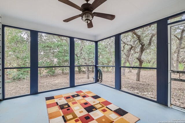 unfurnished sunroom featuring ceiling fan and plenty of natural light