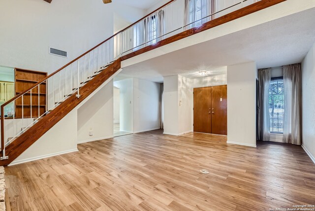 unfurnished living room with a towering ceiling and light wood-type flooring