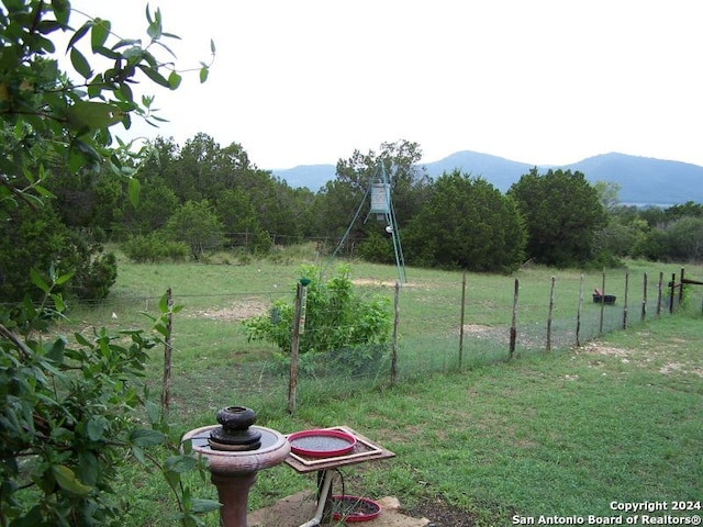 view of property's community with a mountain view, a rural view, and a lawn