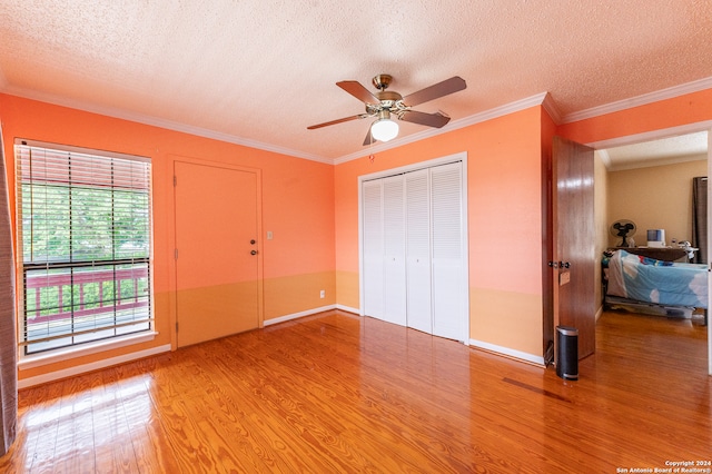 unfurnished bedroom featuring ceiling fan, hardwood / wood-style floors, crown molding, and a textured ceiling