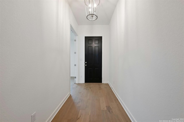 doorway featuring a notable chandelier and light hardwood / wood-style floors