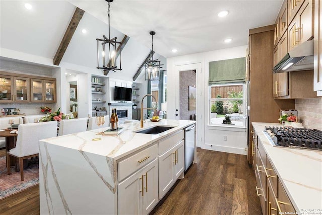 kitchen with appliances with stainless steel finishes, dark hardwood / wood-style floors, lofted ceiling with beams, sink, and a kitchen island with sink