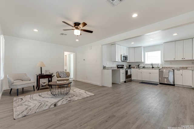 living room with light hardwood / wood-style floors, sink, and ceiling fan