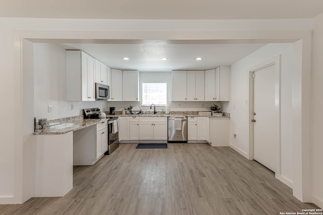 kitchen with sink, white cabinetry, light hardwood / wood-style floors, stainless steel appliances, and light stone counters