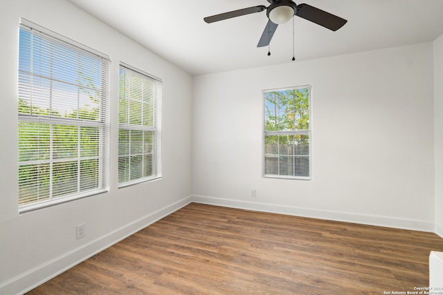 empty room featuring ceiling fan, a healthy amount of sunlight, and dark hardwood / wood-style flooring