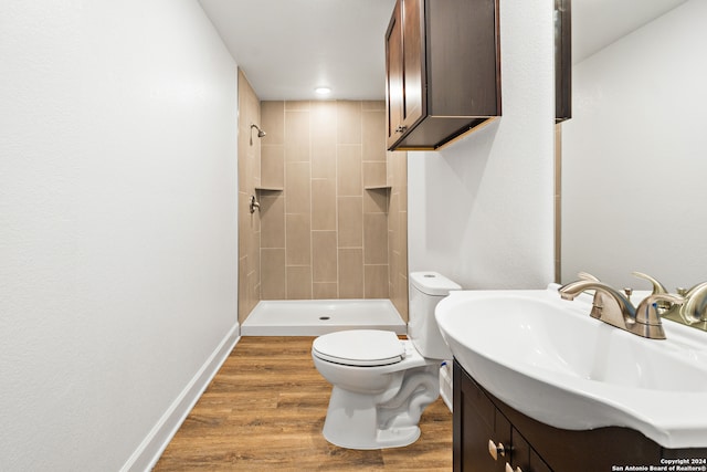 bathroom featuring vanity, tiled shower, wood-type flooring, and toilet