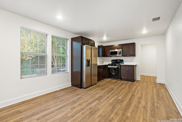 kitchen featuring stainless steel appliances, dark brown cabinets, and light wood-type flooring