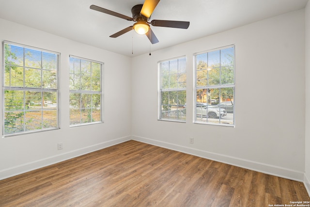 empty room featuring a wealth of natural light, hardwood / wood-style flooring, and ceiling fan