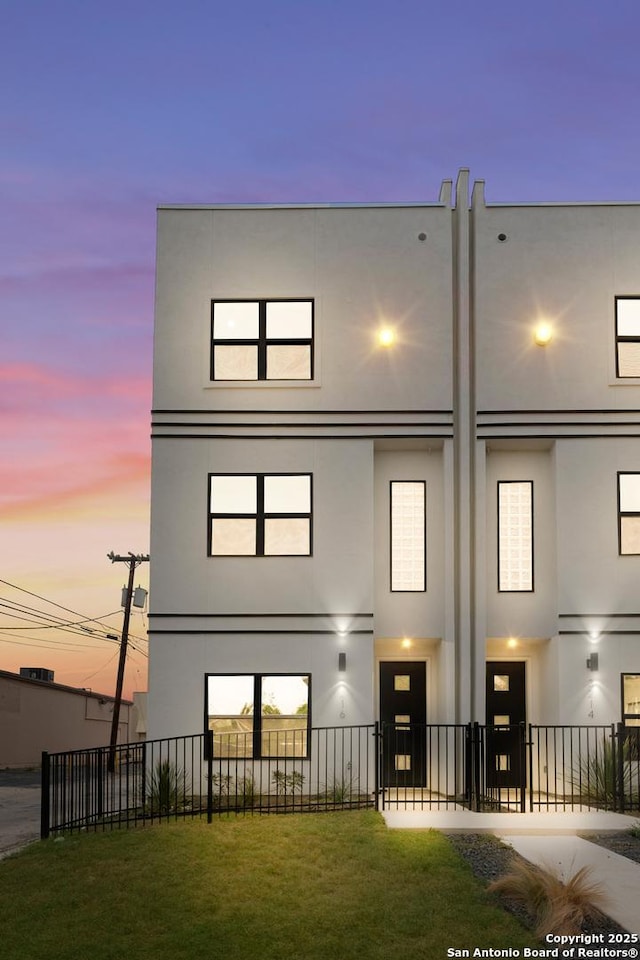 3216 N Elmendorf St, San Antonio, TX 78201 - back of house at dusk featuring a fenced front yard and stucco siding