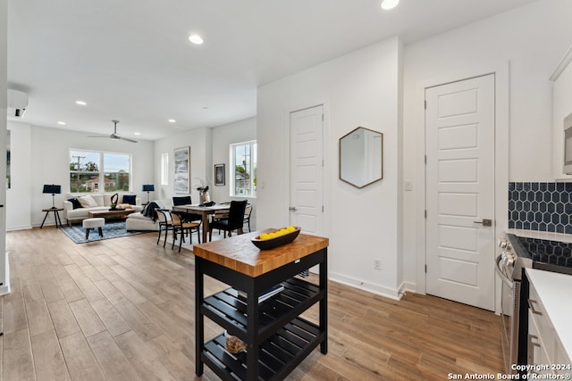 kitchen featuring white cabinets, ceiling fan, light wood-type flooring, and stainless steel stove