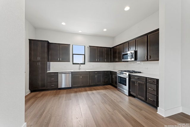 kitchen featuring tasteful backsplash, sink, dark brown cabinets, stainless steel appliances, and light hardwood / wood-style flooring