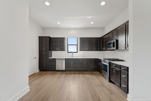 kitchen with appliances with stainless steel finishes, dark brown cabinetry, sink, and light hardwood / wood-style floors