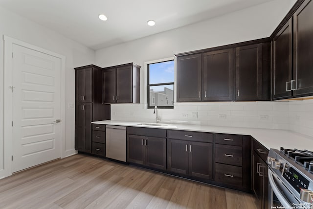 kitchen with tasteful backsplash, sink, light wood-type flooring, dark brown cabinets, and stainless steel appliances