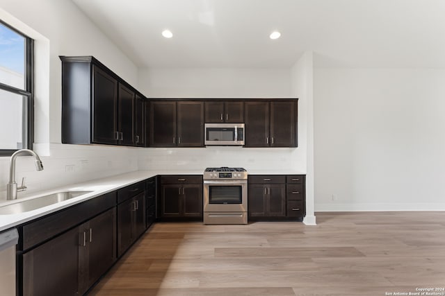 kitchen with light hardwood / wood-style flooring, tasteful backsplash, appliances with stainless steel finishes, and sink